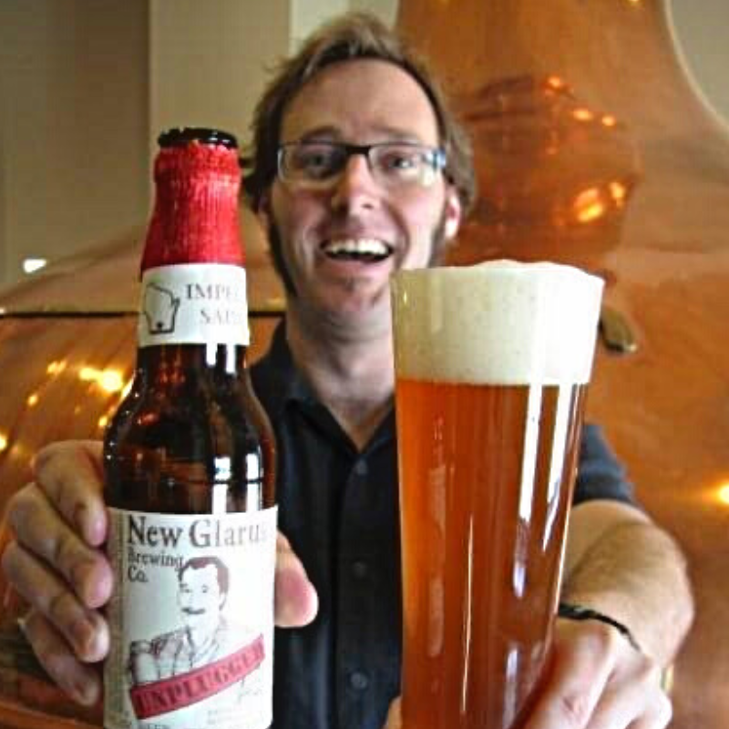 Brewer holding glass of beer and bottle of Imperial Saison.