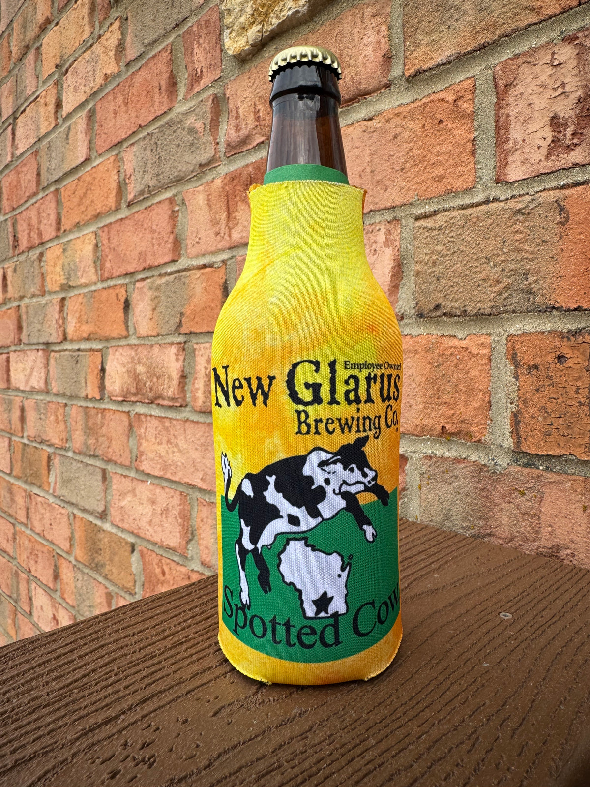 Vibrant yellow bottle koozie with back zipper featuring New Glarus Brewing Co. Spotted Cow logo on front.