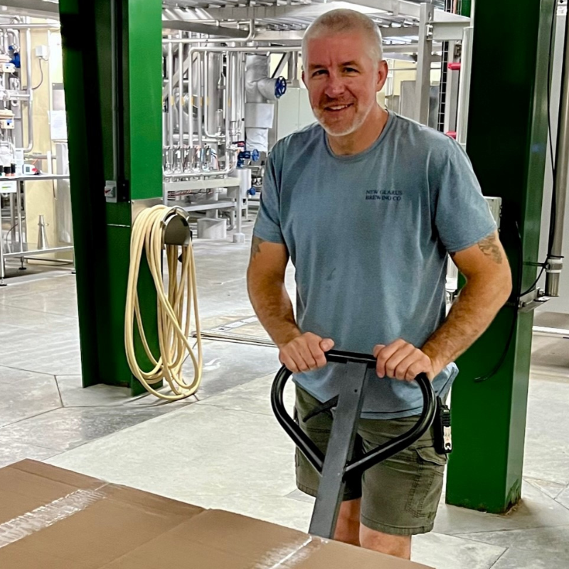 Warehouse team member lifting pallet with pallet jack.