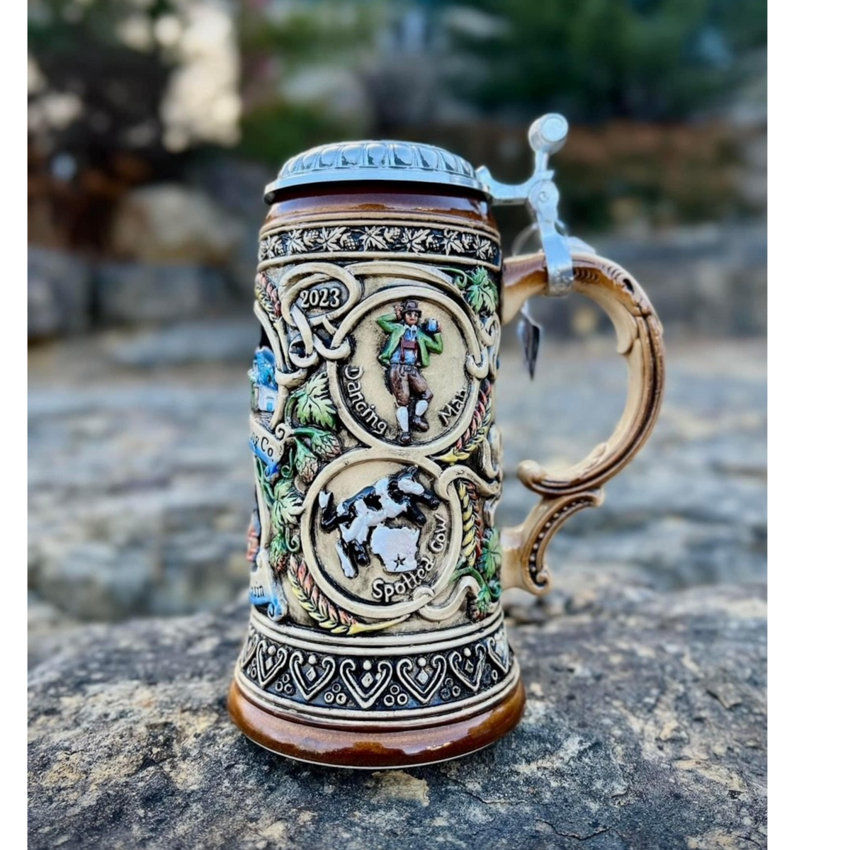 Side of the German Stein with a relief of the Dancing Man logo and the Spotted Cow logo.
